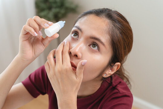 asian young woman using medical eye drops to treat dry eye and irritation.