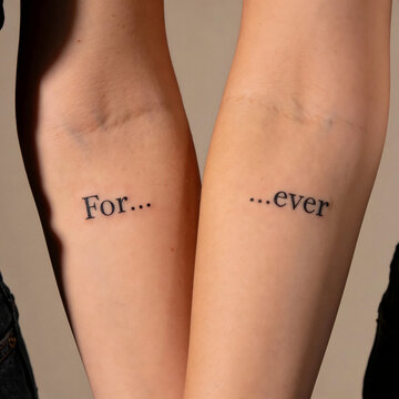 Close-up image showing two arms with identical minimalist tattoos. The clean and simple design emphasizes intimacy, symmetry, and modern graphic aesthetics. The theme is couple and love.