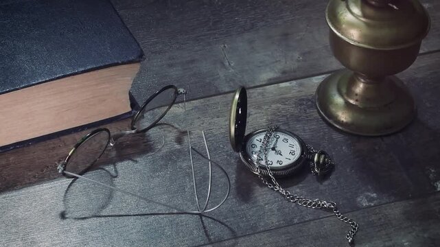 Vintage desk setup with a book, glasses, oil lamp, and pocket watch on display