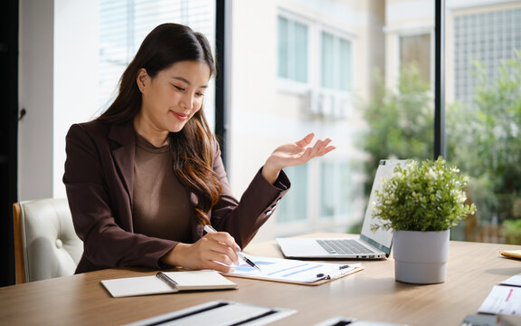 Professional businesswoman presenting ideas while reviewing financial charts and reports during a meeting in a modern office.