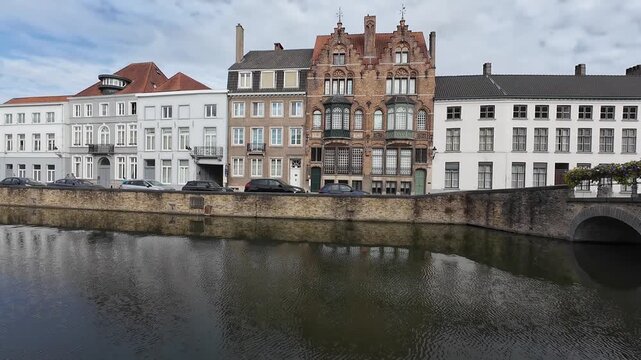 Panning view over canal showcasing traditional architecture in historic center of Bruges, Belgium, morning light