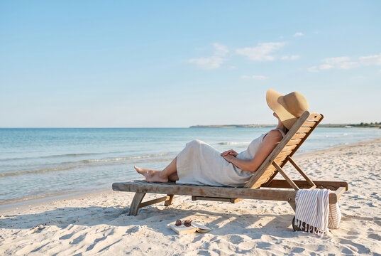 Woman relaxing on beach lounger by the sea during summer vacation