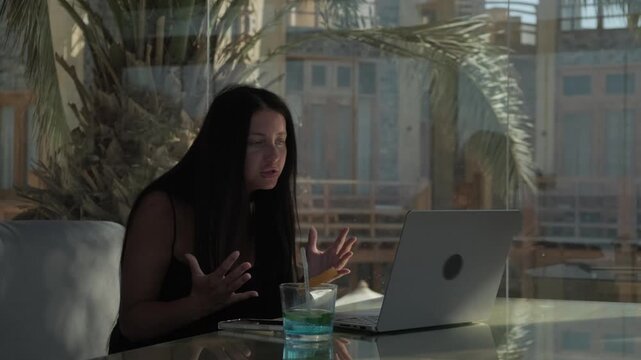 Female freelancer frustrated by stalled creative project closes laptop in disappointment, showing creative block, work stress and professional setback in tropical cafe