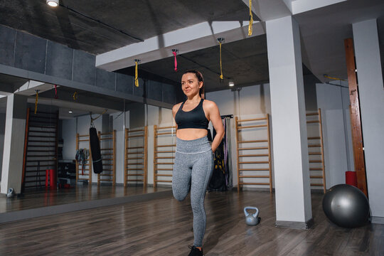 Young woman walking during active recovery in gym. Female athlete staying energized between workout sets concept.