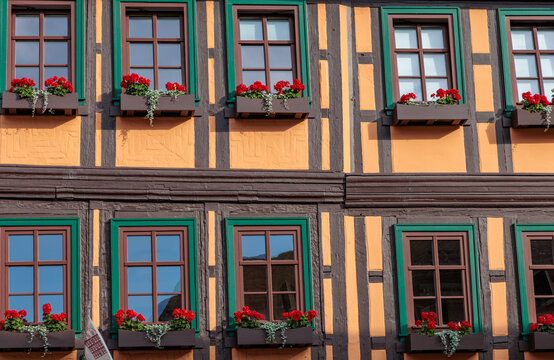 Traditional German half timbered house facade with green windows and red geranium flower boxes in window sill