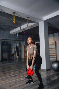 Athletic woman lifting weight with strong athletic posture. Female athlete performing functional strength exercise in gym concept.
