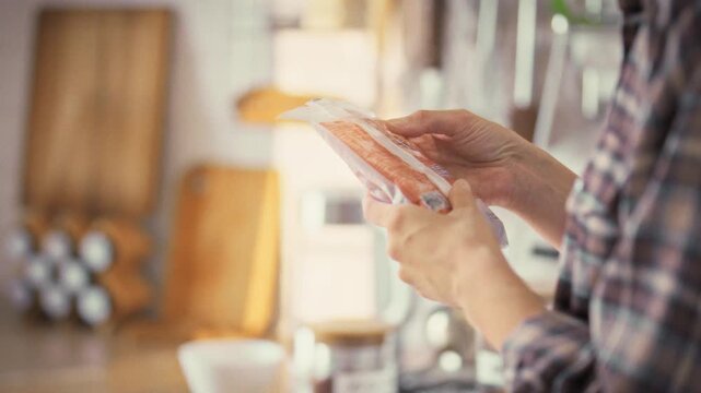 A young woman carefully examines the label on a soft package in her bright home kitchen, checking its composition to ensure proper nutrition and healthcare, reflecting a mindful approach to her diet
