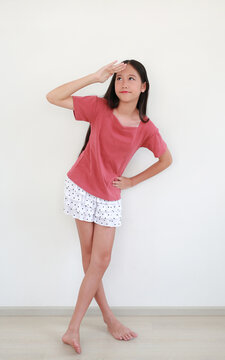Attractive Asian girl curious look, looking far into distance. She is dressed in a short-sleeved pink t-shirt and a short, layered skirt, with her legs elegantly crossed.
