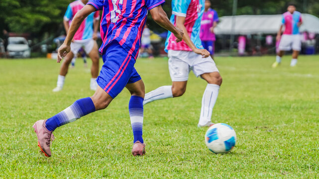 Soccer player dribbling ball during competitive football match on outdoor grass field