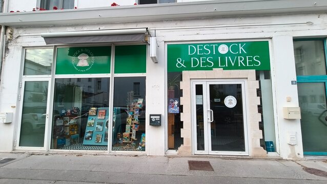 Royan, France - July 15, 2026: Charente-Maritime. Nouvelle-Aquitaine. Green storefront of a bookshop named "Destock & des Livres" with display window showcasing various books and toys