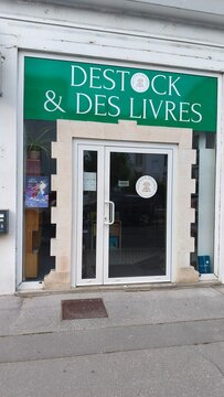 Royan, France - July 15, 2026: Charente-Maritime. Nouvelle-Aquitaine. Bookstore entrance with green sign reading "DESTOCK & DES LIVRES," glass doors, and decorative stone frame in urban setting