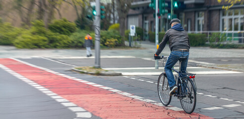 Naklejka premium Man cyclist on red city bike lane. Urban commuting and road safety content.