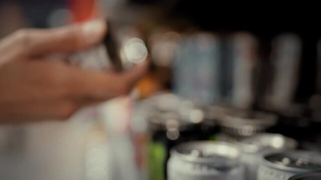 A female hand picks up an aluminium can of carbonated drink from a supermarket shelf carefully choosing among a wide selection of beverages