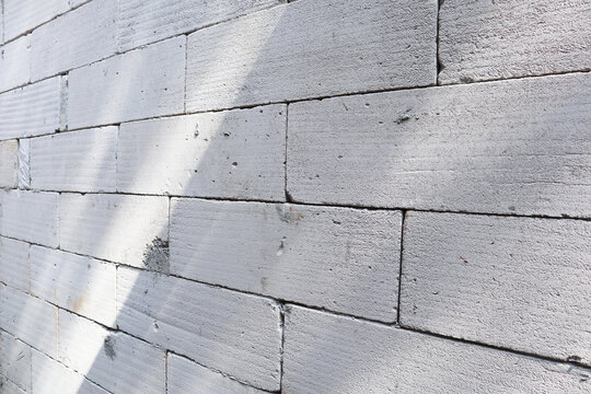 Light gray lightweight concrete block wall texture with diagonal shadows and sunlight. AAC brick