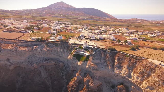 Drone view of Heart of Santorini caldera cliffside with traditional windmill and village landscape in Greece. Santorini, Greece.