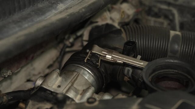 Mechanic using a metal clamp tool on car radiator hose.