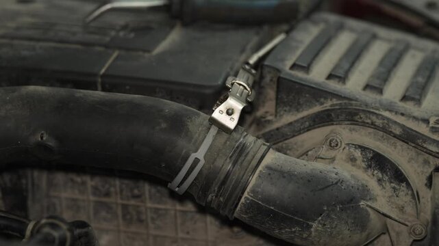 Mechanic using a metal clamp tool on car radiator hose.