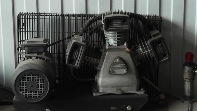 Industrial air compressor unit with electric motor inside professional workshop.