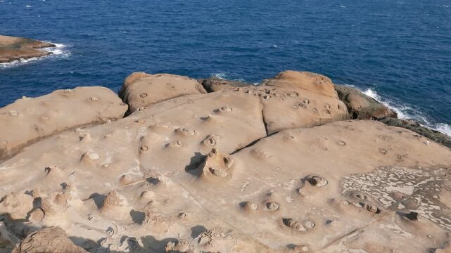 Surreal weathered rocky shore, Yehliu Geopark cape shelf, quick pan right, sunny day, beautiful coloured waters of The East China Sea on the background.