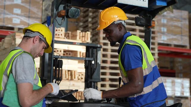 Workers check inventory at warehouse while using a device to track supplies