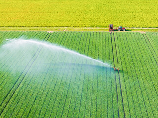 Obraz premium Aerial drone view of agricultural field with irrigation system watering crops. Center pivot irrigation machine spraying water on agricultural land.