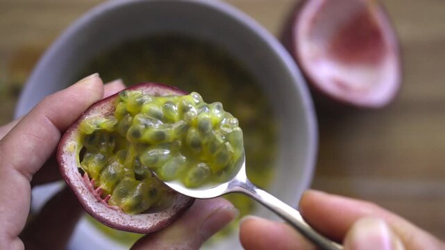 Scooping passion fruit pulp into a bowl