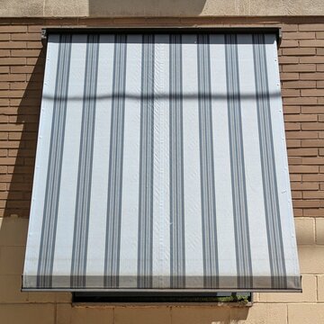 Vista de cerca de un toldo de tela rayada instalado para proteger una ventana de un edificio de los rayos de sol en verano 