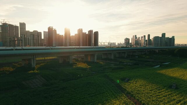 Aerial view of a high speed train travels on an elevated track past tall apartment buildings in China