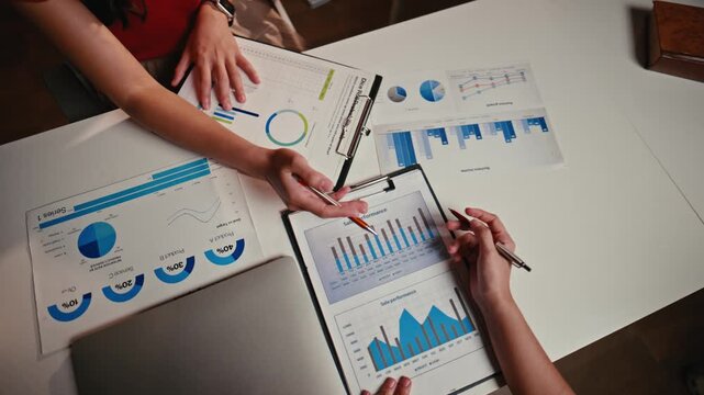 Top view of two female colleagues analyzing financial reports. Business partners brainstorming and planning marketing strategy in the office