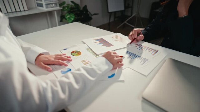 Two business professionals analyzing market data reports and financial documents together during a late-night office meeting