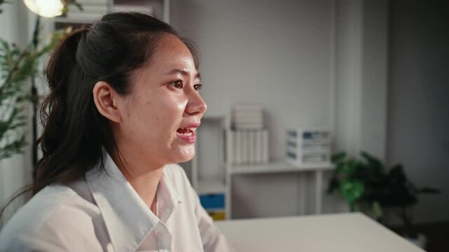 Young Asian businesswoman smiling and happily talking during a job interview or meeting in a modern office, showing confidence