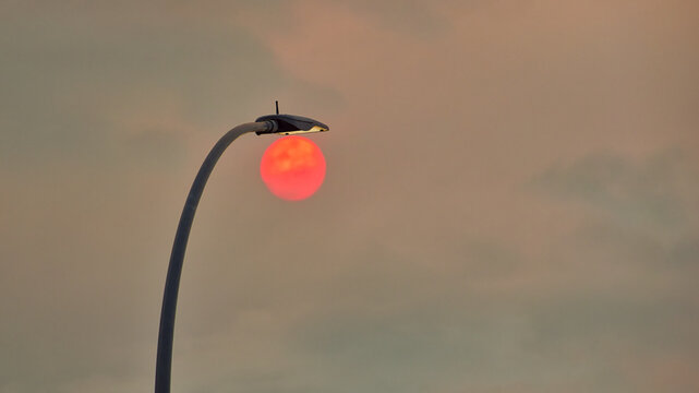 A red sun, filtered through smoke from wildfires in Madrid, &Aacute;vila and Toledo, appears behind a street light in Arroyomolinos, Spain.