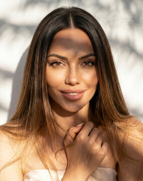 Close-up portrait of a beautiful young brunette woman with long hair bathed in sunny shadows