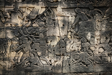 Fototapeta premium Ancient sandstone bas-relief depicting a historical battle and warriors on the walls of Bayon Temple in Angkor Thom, Siem Reap, Cambodia