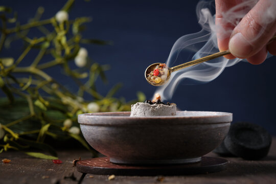 Incense ritual on Yule - placing frankincense with a spoon on a glowing incense charcoal