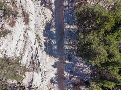 Aerial view of a mountain landslide showing exposed rock, debris flow, and fallen trees on a steep slope in Cortina d'Ampezzo, Veneto, Italy.