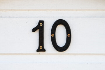 Black metal number 10 mounted on white timber beach hut wall © Jane Allan