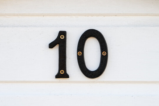 Black metal number 10 mounted on white timber beach hut wall