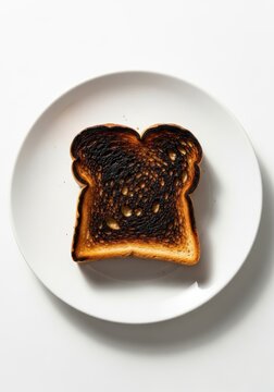 Single Slice of Heavily Burnt and Charred Toast on a White Ceramic Plate Isolated on White Background