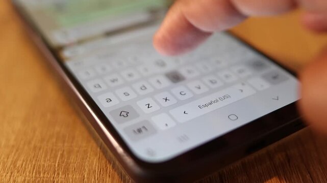 Unrecognizable person typing on a smartphone touchscreen keyboard while sending a text message on a social media application