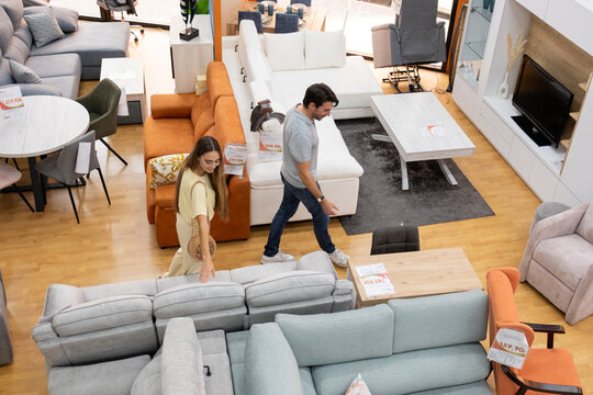 Young couple exploring different sofas and tables in a modern furniture store