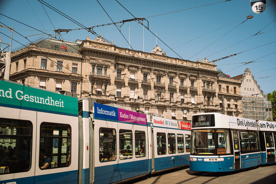 Zurich, Switzerland, August 4, 2026. A blue public transit tram passes through Paradeplatz square in front of UBS building.