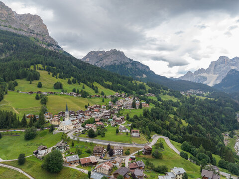 Aerial view of the alpine village of Selva di Cadore with its historic church, green meadows, and winding roads nestled in the Dolomites, Selva di Cadore, Veneto, Italy.