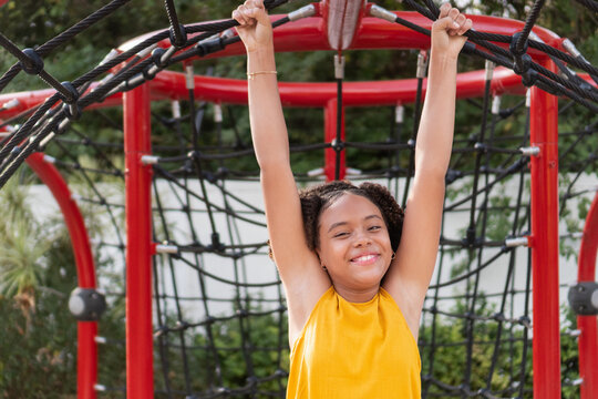 Teenager playing on playground climbing net