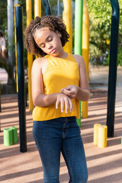 Teen girl with curly hair looking pensive in playground