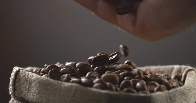 Roasted coffee beans falling into a burlap sack in slow motion macro