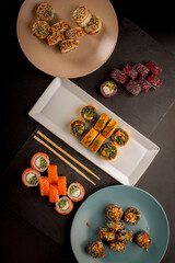 Assorted sushi rolls arranged on dark slate board and blue plate with chopsticks © Ilias