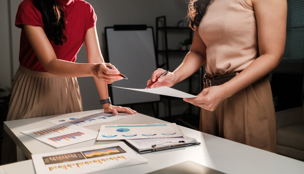 Businesswomen discussing data and signing document in office