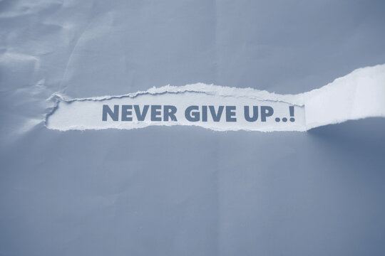 The words "NEVER GIVE UP" are written on the back of a torn piece of paper&mdash;a motivational message to keep going and not give up.
