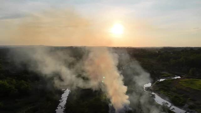 An aerial view at sunset of a fire producing heavy smoke that is causing deforestation in the Amazon rainforest.